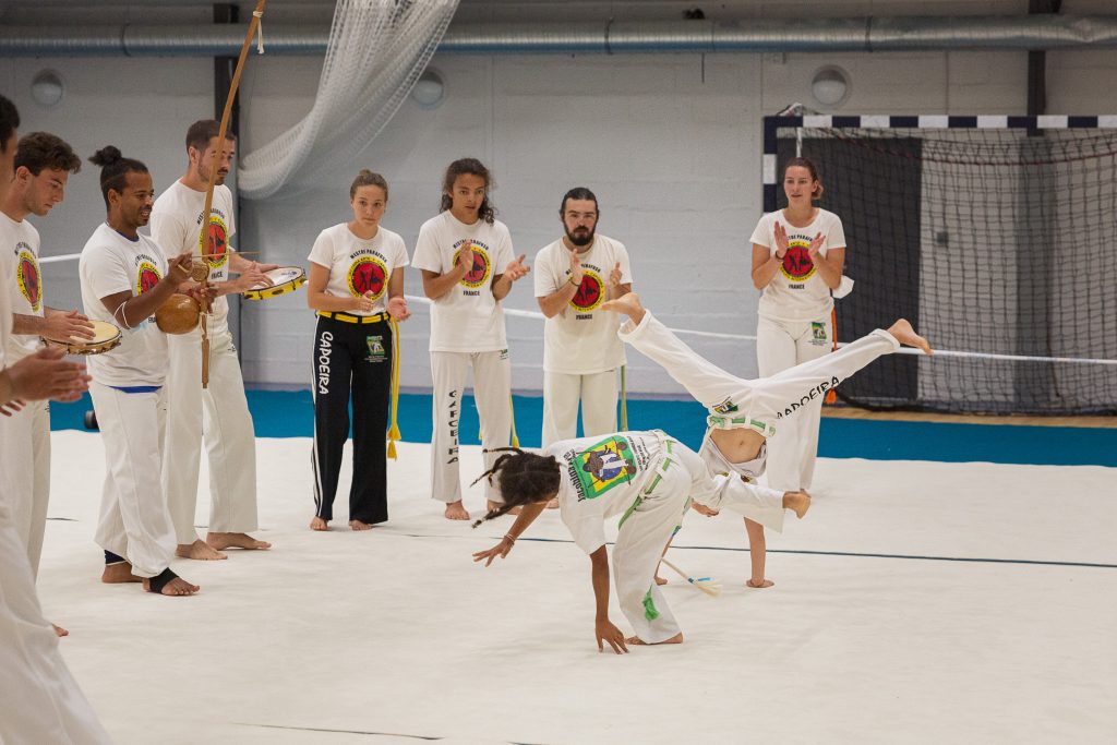 Roda de capoeira Jacobina Arte à Nantes : une élève fait un mouvement au sol pendant que le groupe joue et chante